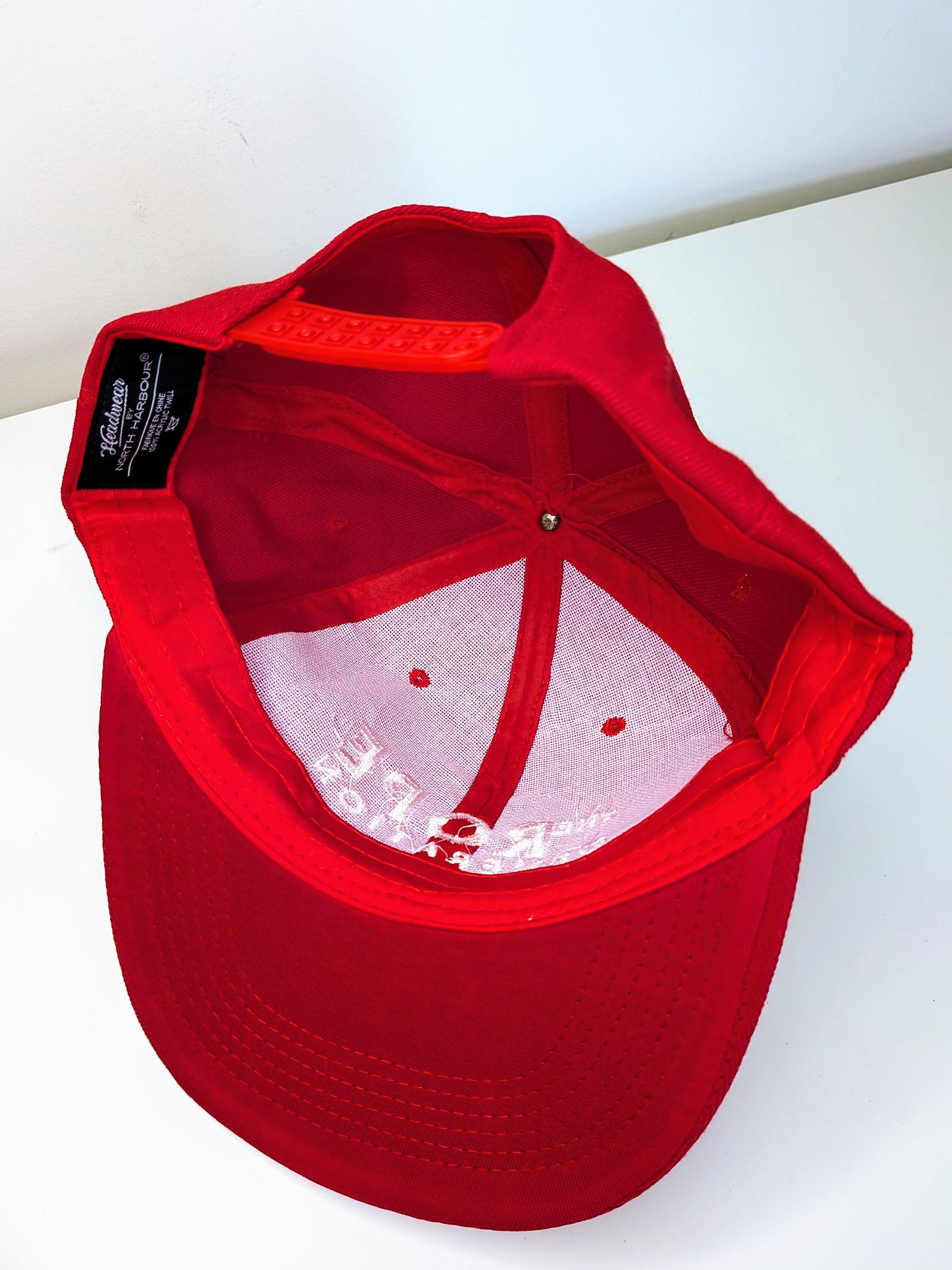 Underside of a red flat brim snap back cap