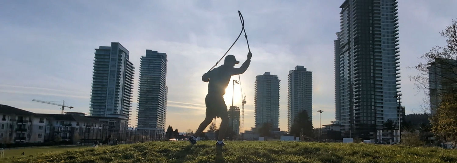 Silhouette of a guy doing rope flow on a hill in the sunset